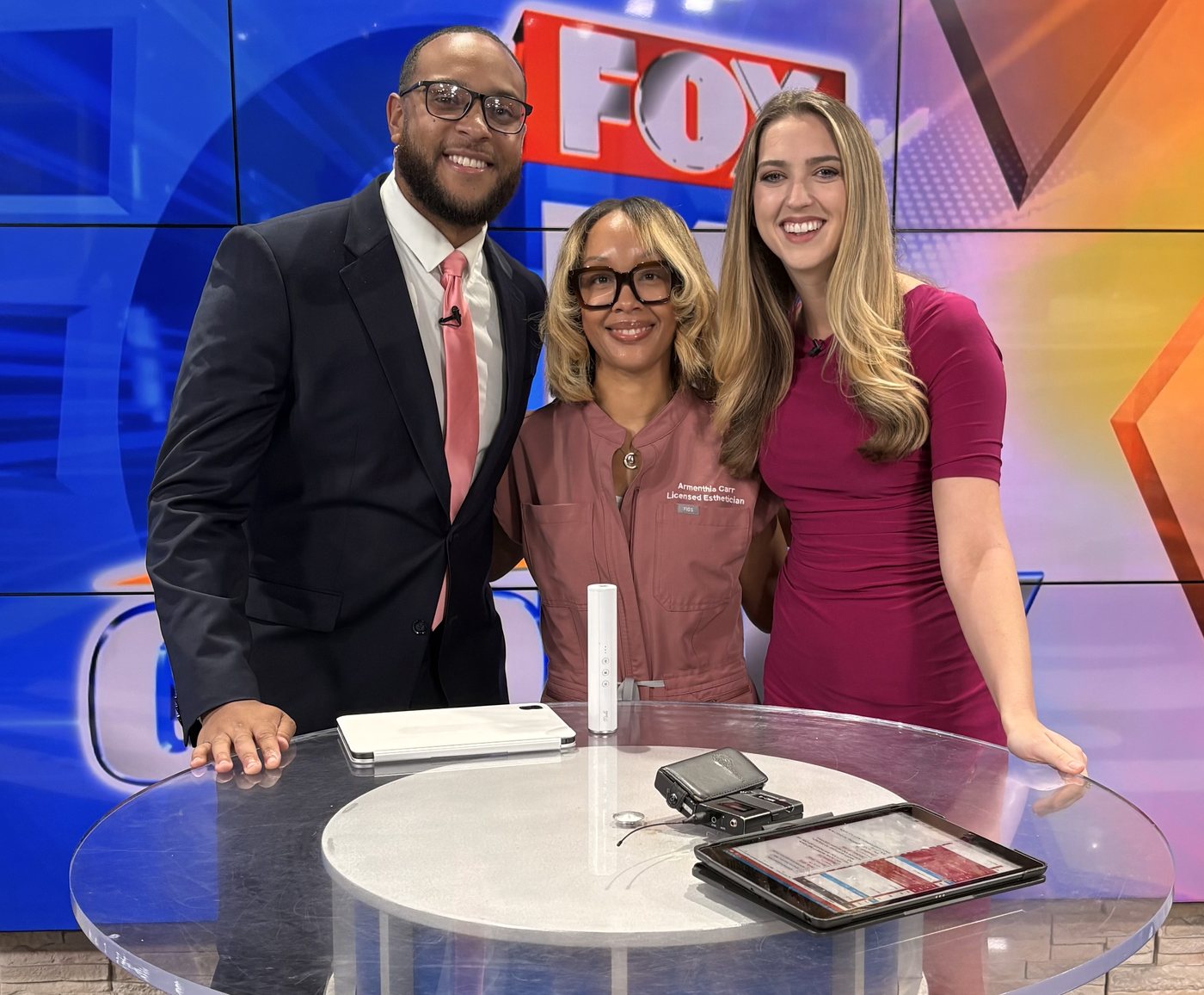 Armenthia Carr on a television news set, with the Muilli device and a tablet on the desk.